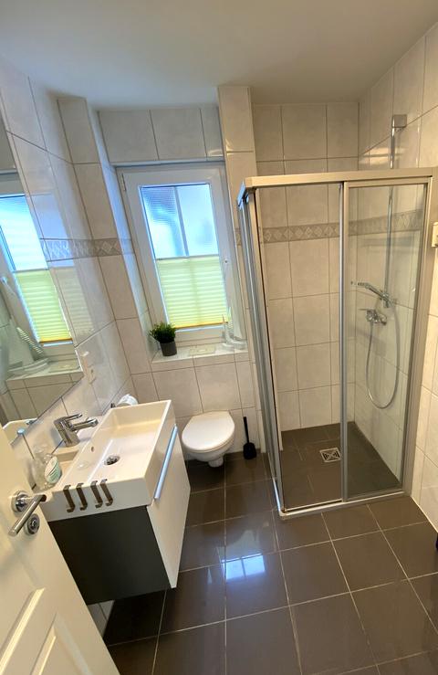 Helles Hauptbad mit bodengleicher Dusche, Waschtisch und WC
