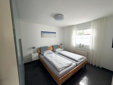 Schlafzimmer mit Doppelbett aus Holz und Ostsee-Wandbild