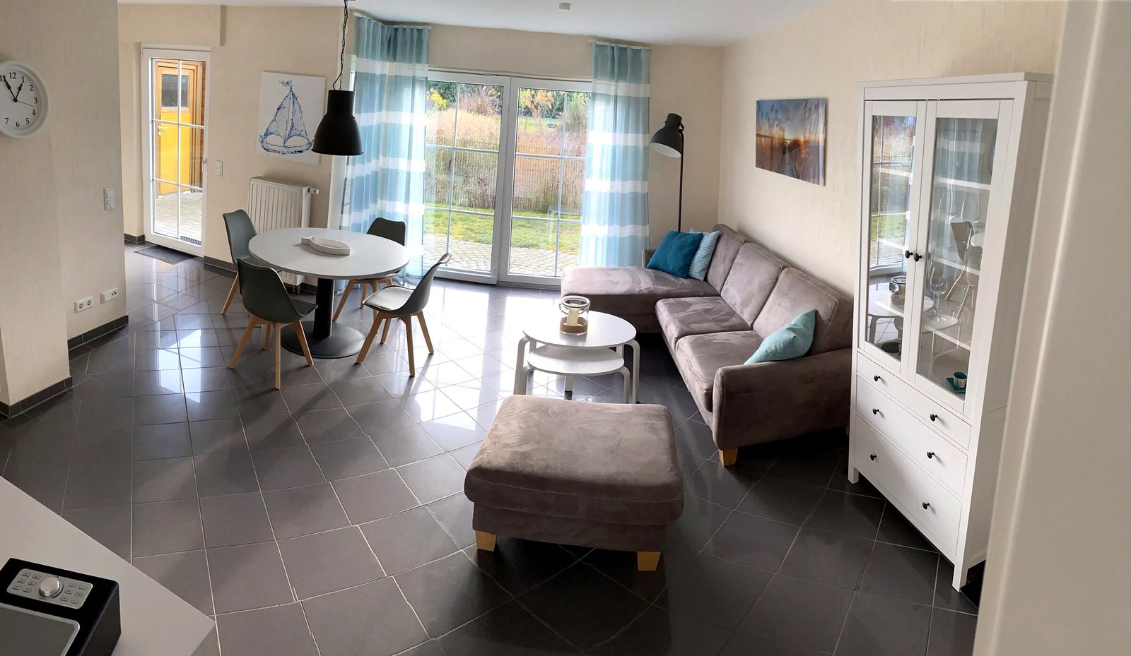 Heller Wohn- und Essbereich der Ferienwohnung Nele in Zempin mit Esstisch, Sofa und bodentiefer Terrassentür